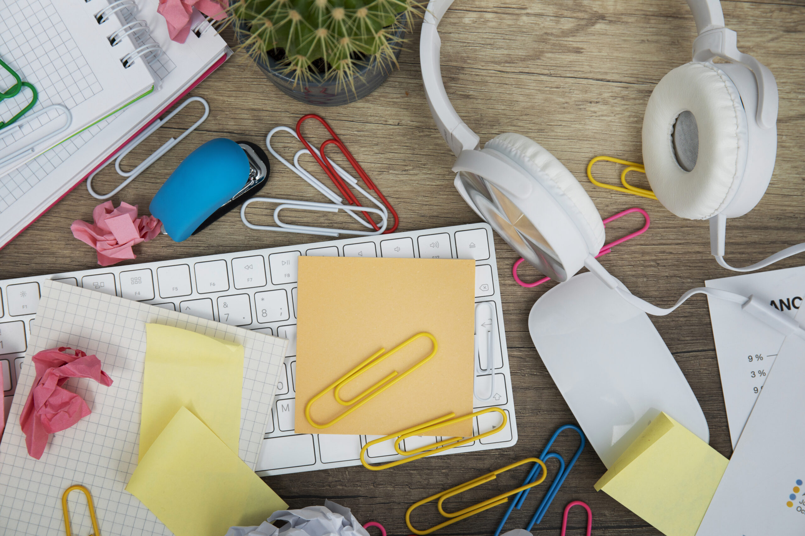 słuchawki, klawiatura, spinacze, kolorowe karteczki porozrzucane na stole
